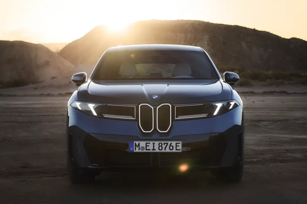 BMW i5 elektrische auto met een woestijnlandschap bij zonsondergang op de achtergrond.