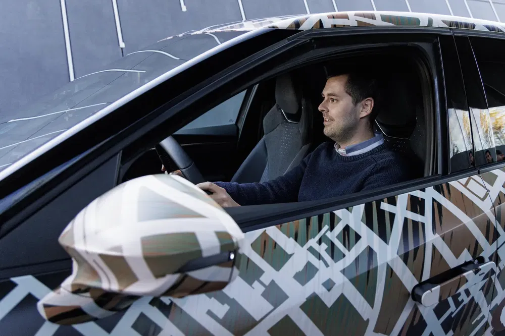 Man die moderne SUV met uniek geometrisch camouflagepatroon bestuurt.