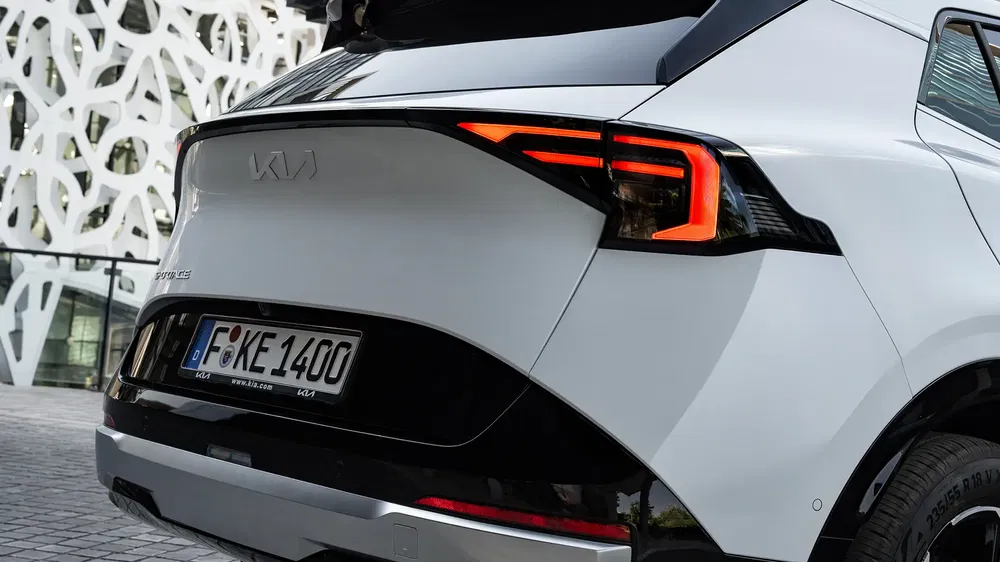 Arrière d'un Kia Sportage blanc moderne avec feux LED distinctifs et plaque allemande.