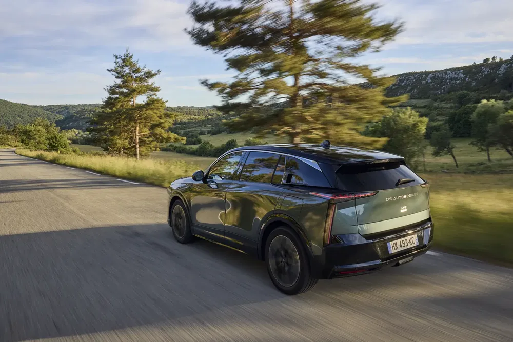 Elektrische SUV DS rijdt door het groene landschap op een schilderachtige weg.