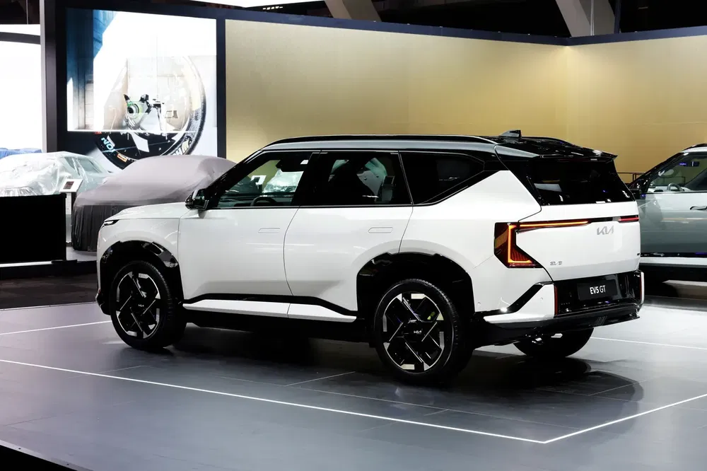 SUV Kia EV9 blanc sur scène d'exposition avec design moderne et lignes élégantes.