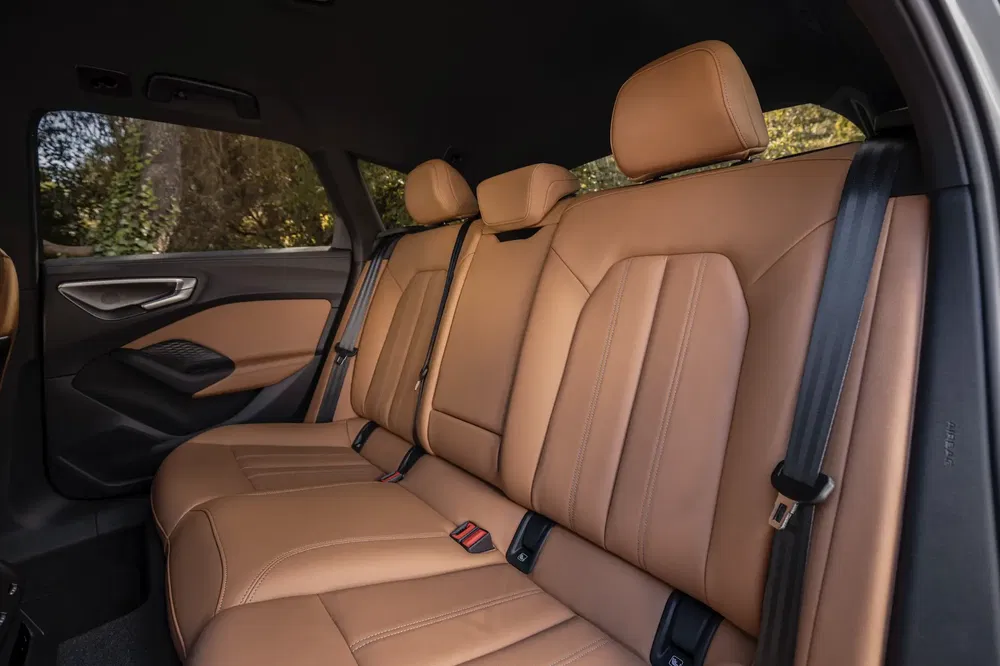 Intérieur de voiture avec sièges arrière en cuir marron, design moderne et spacieux.
