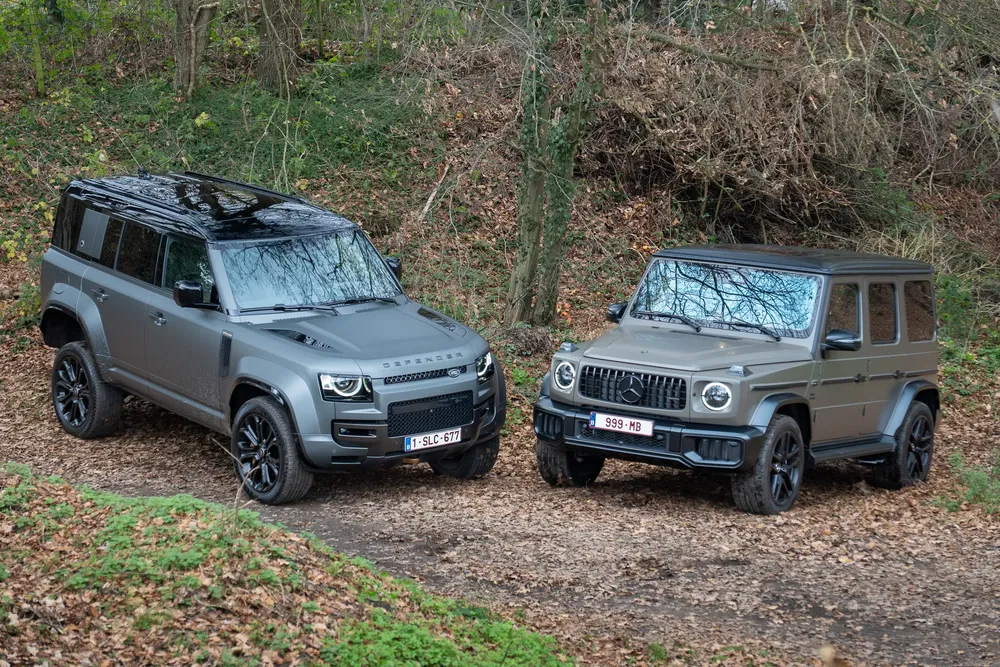 {"fr":"Land Rover Defender et Mercedes-Benz G-Class garées en forêt, automne, feuilles mortes visibles.","nl":"Land Rover Defender en Mercedes-Benz G-Klasse geparkeerd in bos, herfst, gevallen bladeren zichtbaar."}