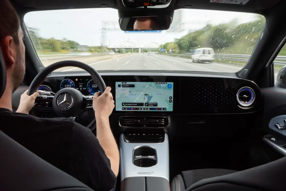 Intérieur d'une Mercedes avec grand écran de navigation sur autoroute.