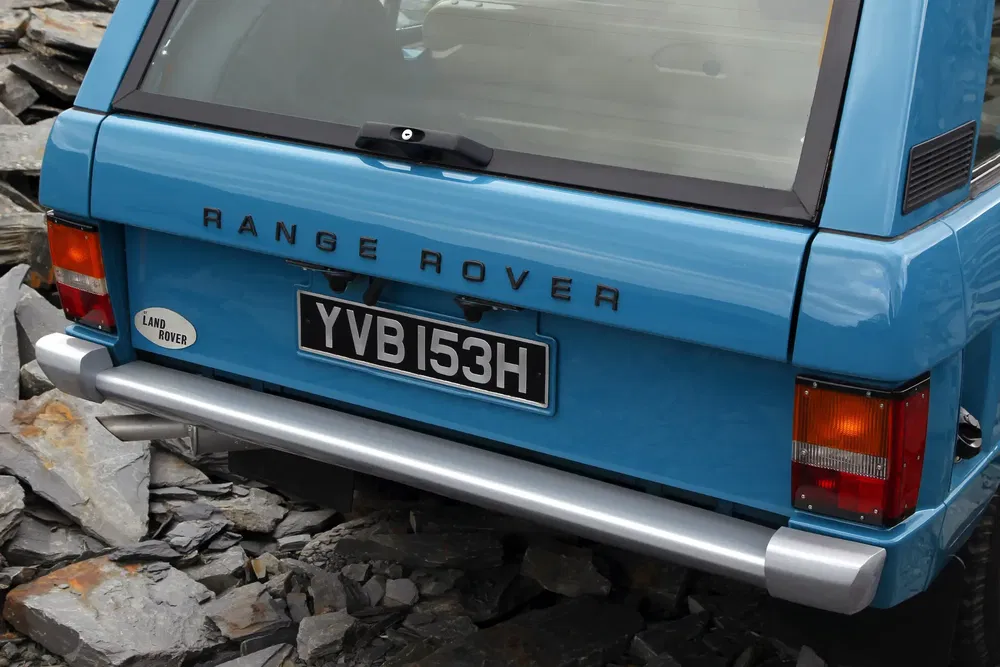 Arrière d'un Range Rover classique bleu sur terrain rocheux, plaque d'immatriculation YVB 153H.
