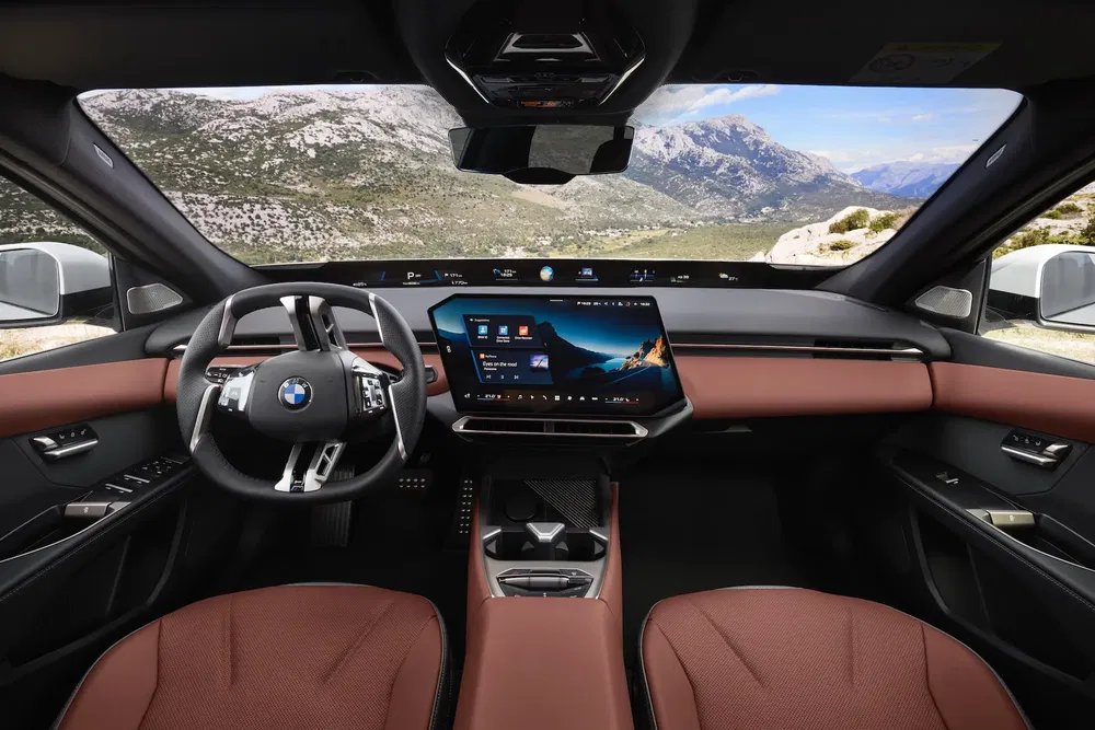 Intérieur moderne de BMW avec tableau de bord numérique et vue panoramique sur montagnes.