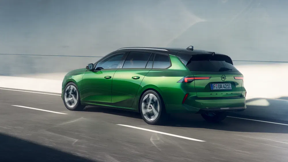 Opel Astra Sports Tourer in felgroen op zonnige weg, elegant en modern design.