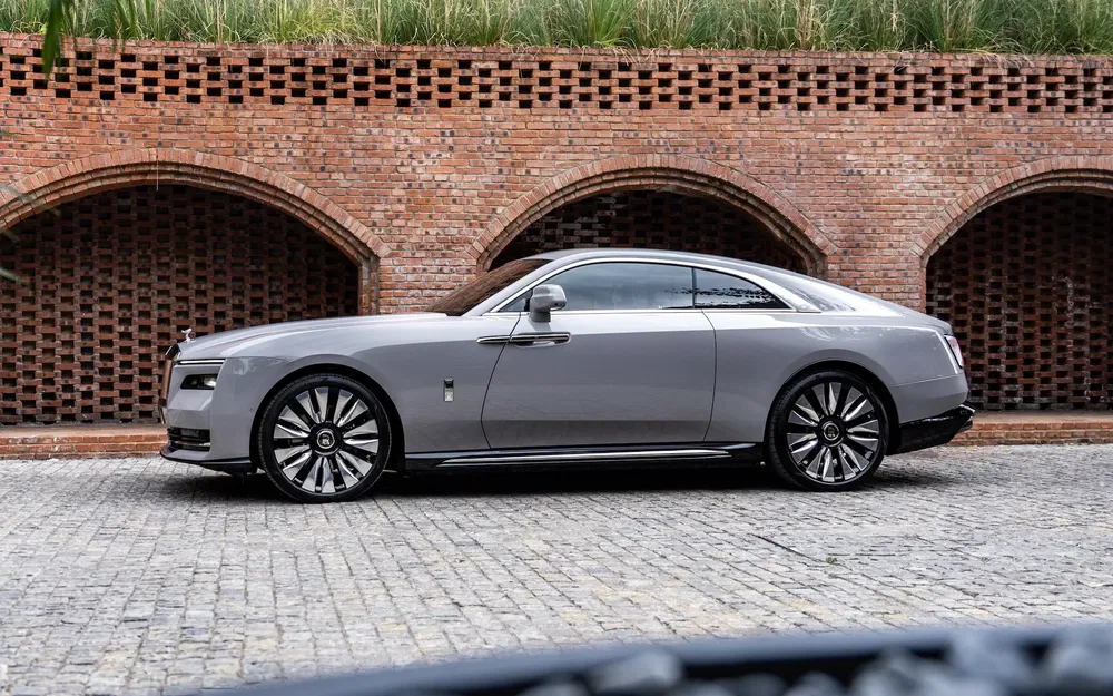 Coupe Rolls-Royce grise élégante devant un mur de briques texturé.