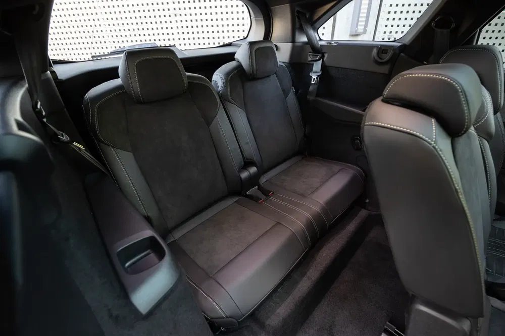 Auto-interieur met stoffen achterstoelen, derde rij opgevouwen.