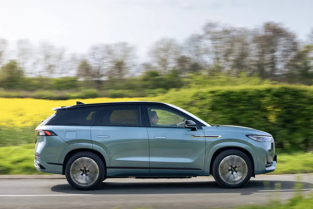 SUV électrique Xpeng G9 roulant sur route de campagne verdoyante par temps clair.