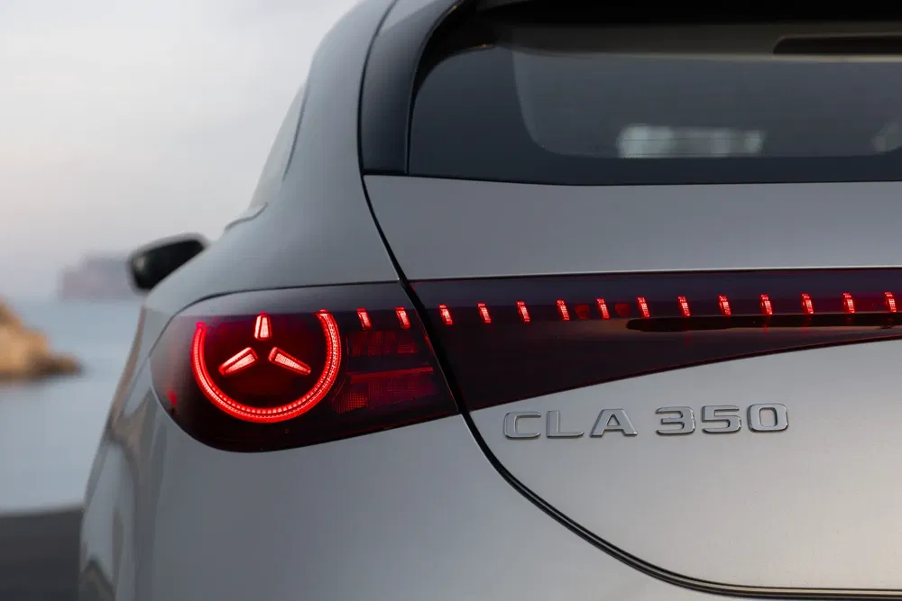Feu arrière et badge Mercedes CLA 350 au bord d'une route côtière.