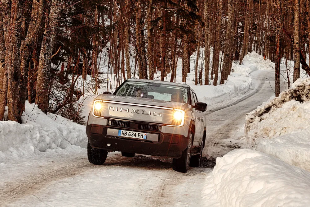 Maxus T90 traversant un chemin enneigé entouré d'arbres en hiver.