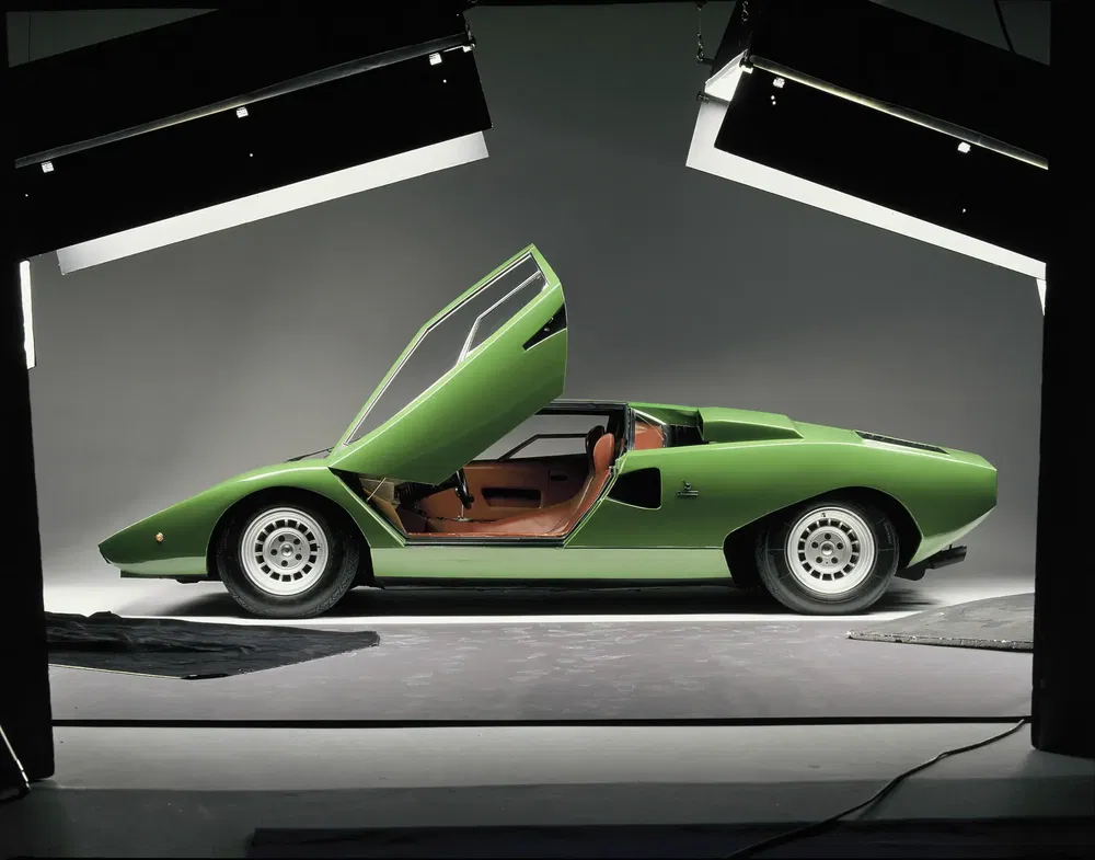 Groene Lamborghini Countach, vleugeldeuren open, in studio onder professionele verlichting.