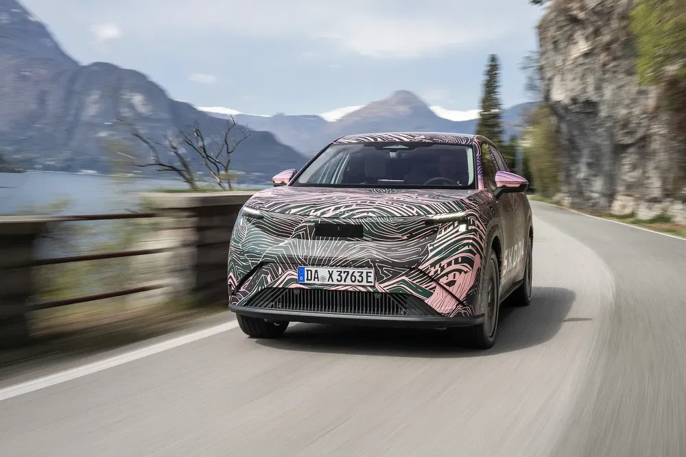 Geïncamoufleerde conceptauto op bergweg langs schilderachtig meer.