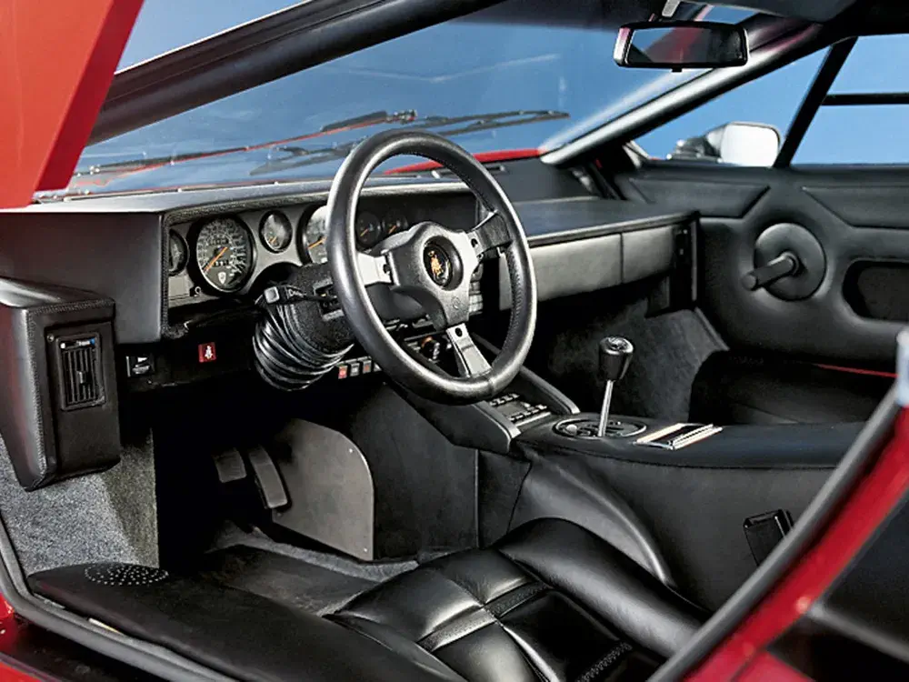Interieur van een Lamborghini Countach met klassiek dashboard en iconisch stuurwiel.