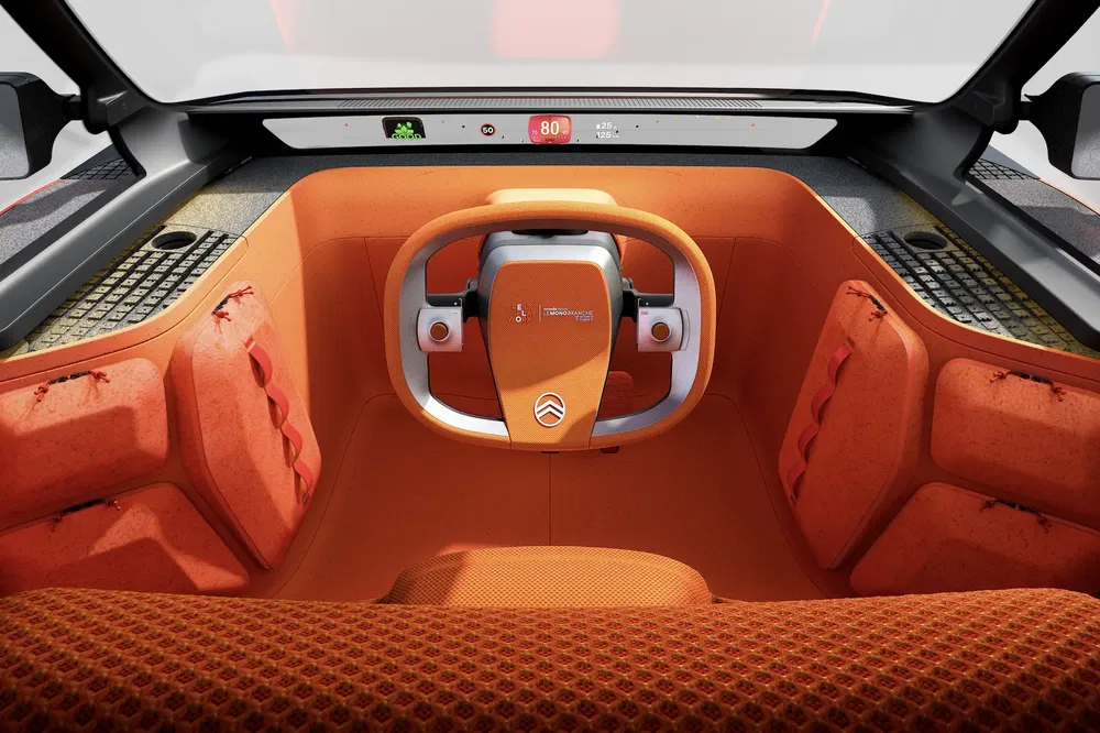 Intérieur futuriste du concept-car Citroën Oli, avec volant minimaliste et tableau de bord numérique.