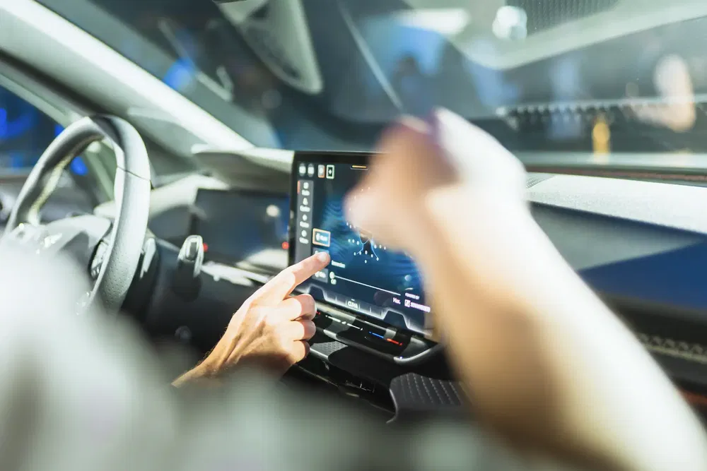 Hand bedient touchscreen van moderne auto, toont multimedia-interface.