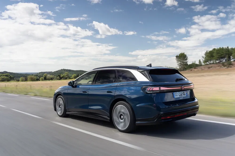 Volkswagen ID.7 break roulant sur une route panoramique par temps clair et ensoleillé.