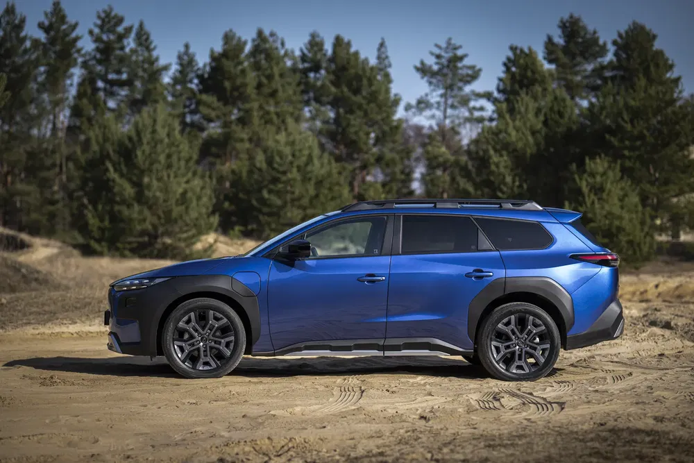 SUV Citroën C5 Aircross bleu sur chemin de terre, entouré d'arbres.