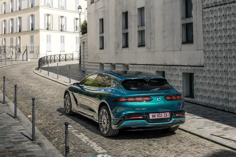 Fisker Ocean GT vert sur une rue pavée dans un quartier résidentiel moderne.