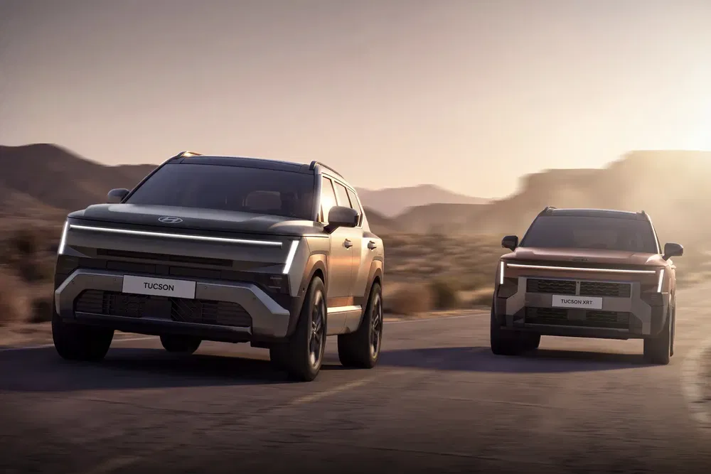 Deux Hyundai Tucson modernes roulant sur une route désertique au crépuscule.