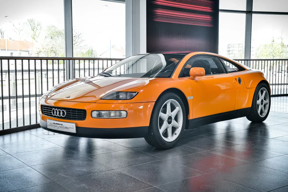 Oranje Audi Quattro Spyder tentoongesteld in een moderne, lichte showroom.
