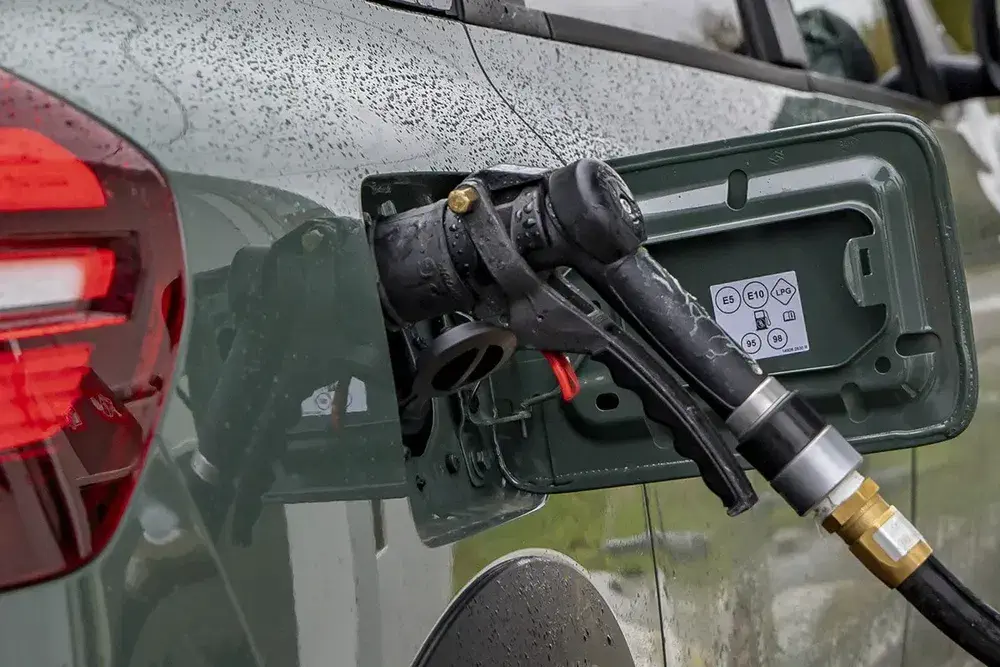 Bouchon de réservoir de voiture avec illustration de types de carburant compatibles, sous la pluie.
