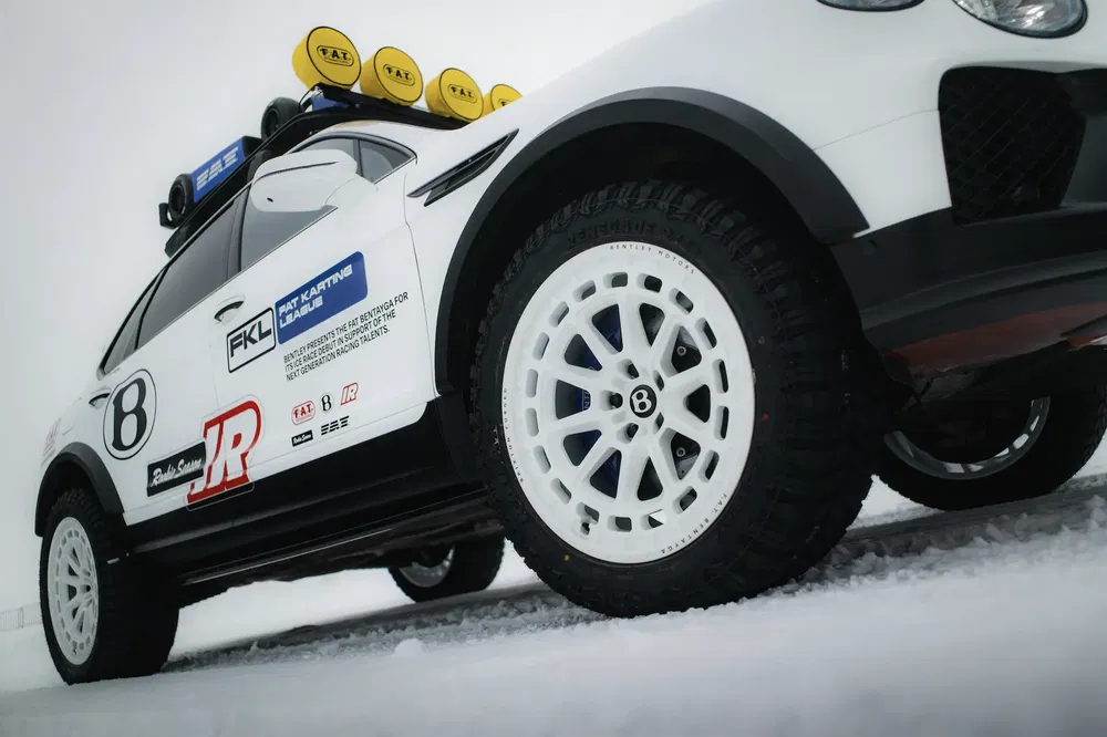 Bentley Bentayga rallyewagen op sneeuw, extra lichten en witte terreinbanden.