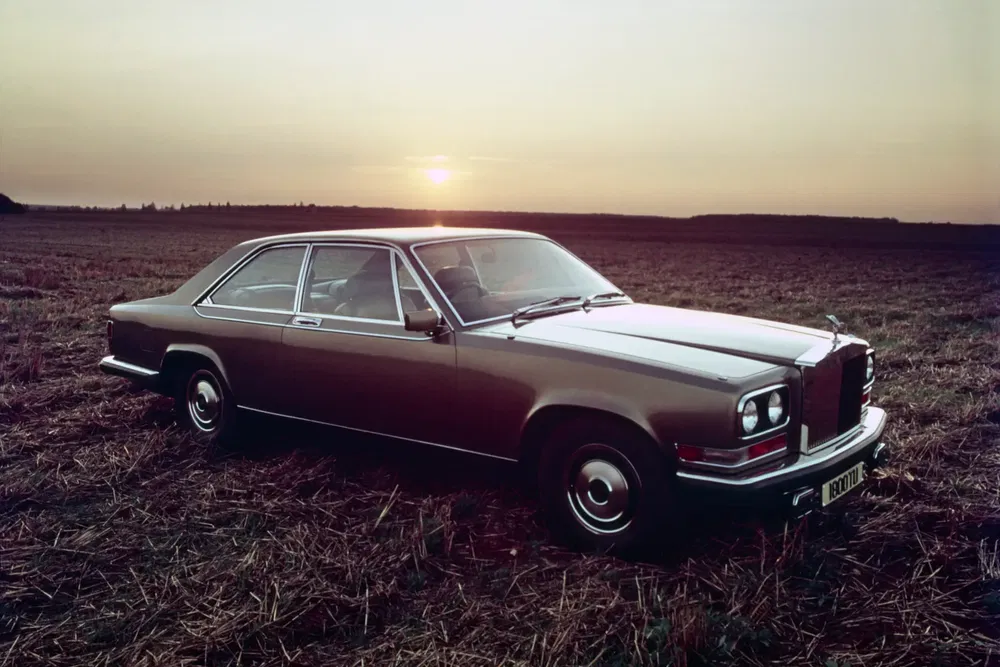 Bentley T1 classique garée sur un champ au coucher du soleil, design élégant et intemporel.