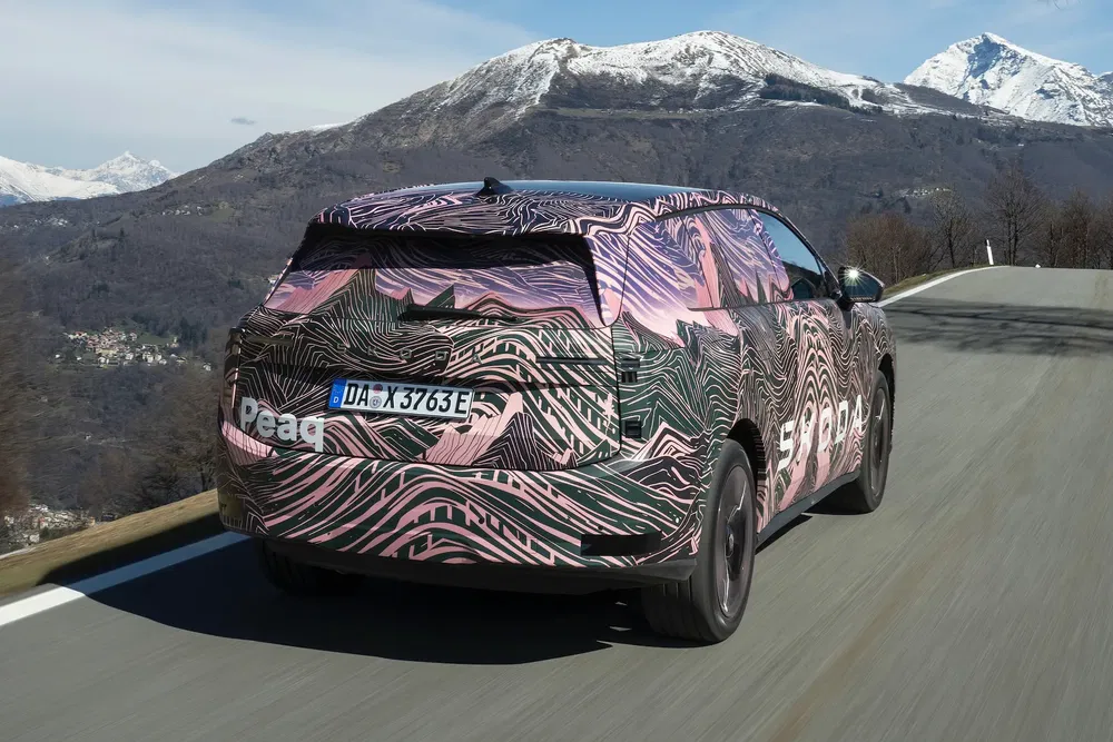 Škoda prototype met camouflage op bergweg met besneeuwde achtergrond.