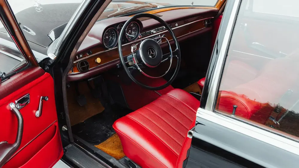 {"fr":"Intérieur d'une Mercedes-Benz vintage au design classique avec sièges en cuir rouge.","nl":"Klassiek interieur van een vintage Mercedes-Benz met rode lederen stoelen."}
