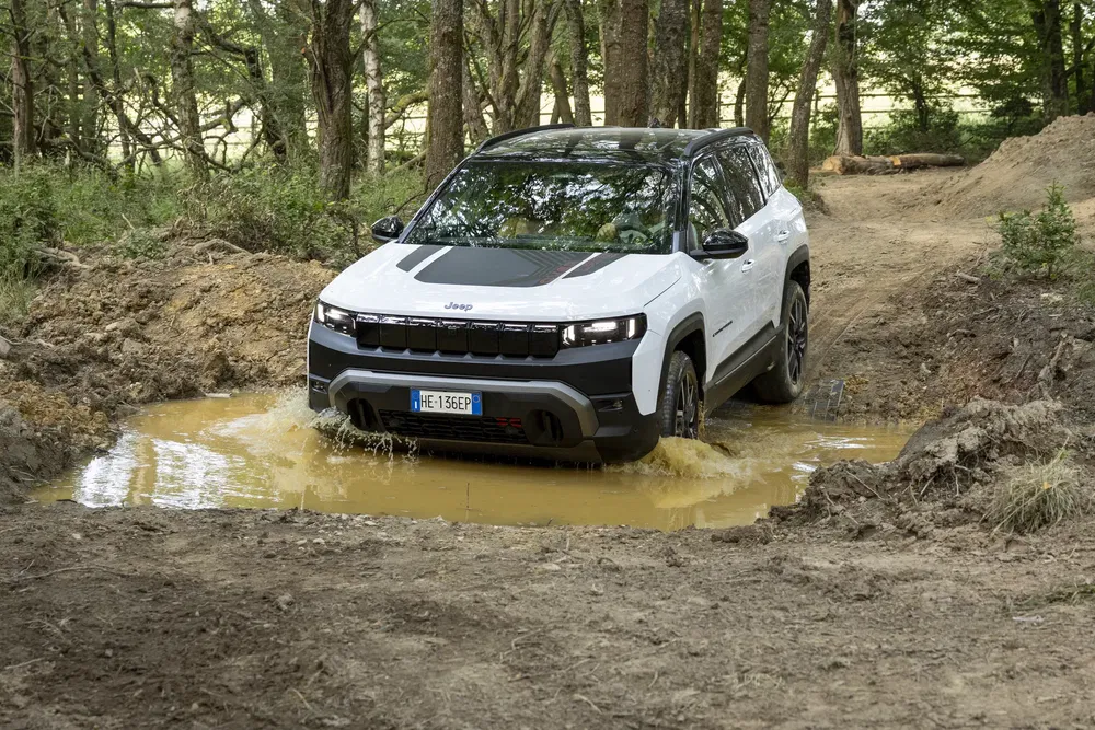 Jeep 4x4 traversant un chemin boueux dans une forêt dense.
