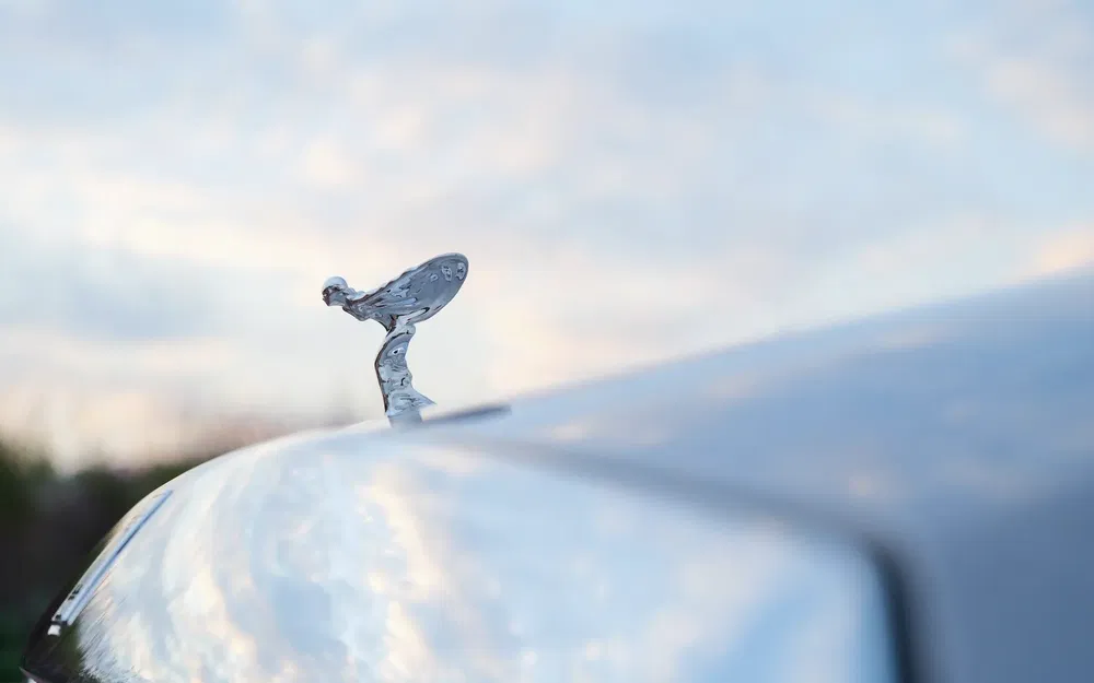 Ornement de capot Spirit of Ecstasy d'une Rolls-Royce sur fond de ciel nuageux.