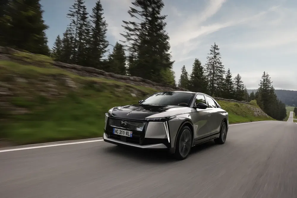 Zwarte DS 4 elektrische auto rijdt op een schilderachtige bospad.