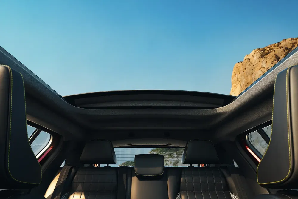 {"fr":"Vue intérieure d'un véhicule avec toit panoramique ouvrant sous ciel bleu clair.","nl":"Interieur van een voertuig met open panoramisch dak onder heldere blauwe lucht."}