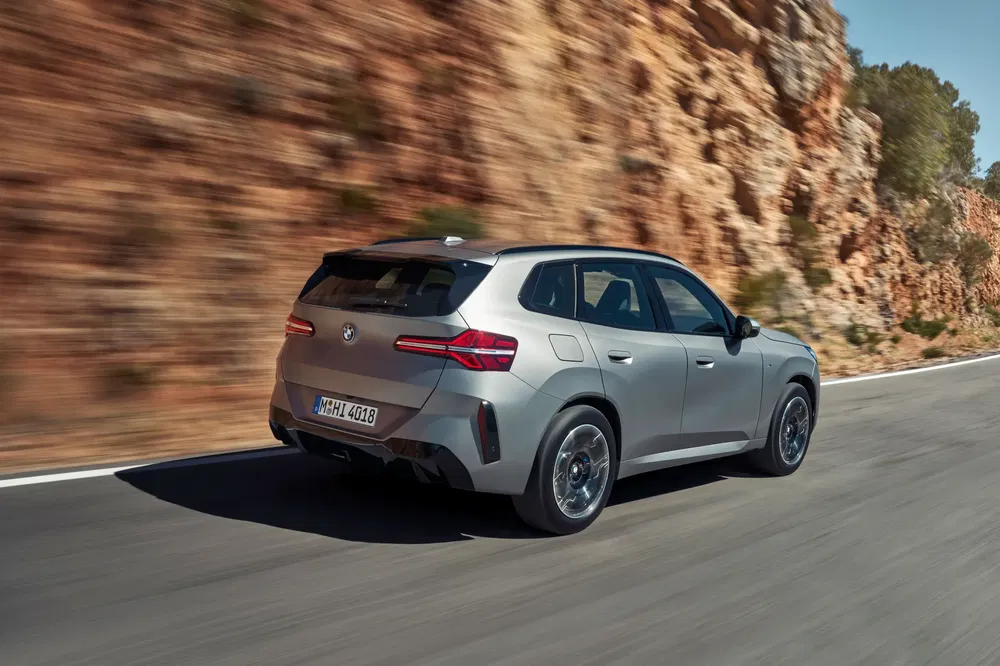 SUV BMW X3 de couleur argent sur une route de montagne sinueuse, arborant un design élégant.