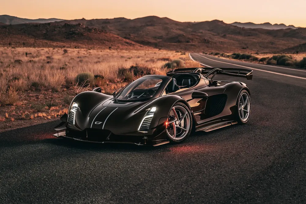 Supercar Czinger 21C noire sur une route désertique au coucher du soleil.