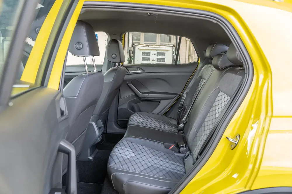 Interieur van een gele Volkswagen T-Cross met stoffen achterstoelen met patroon.