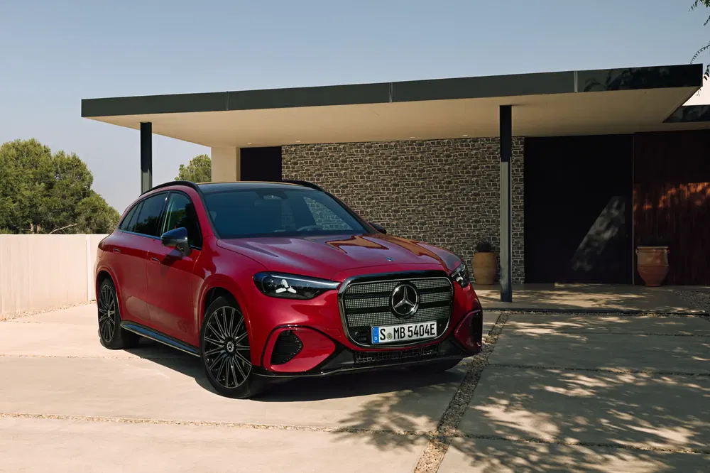 Mercedes-Benz rouge garée devant une maison moderne avec façade en pierre.