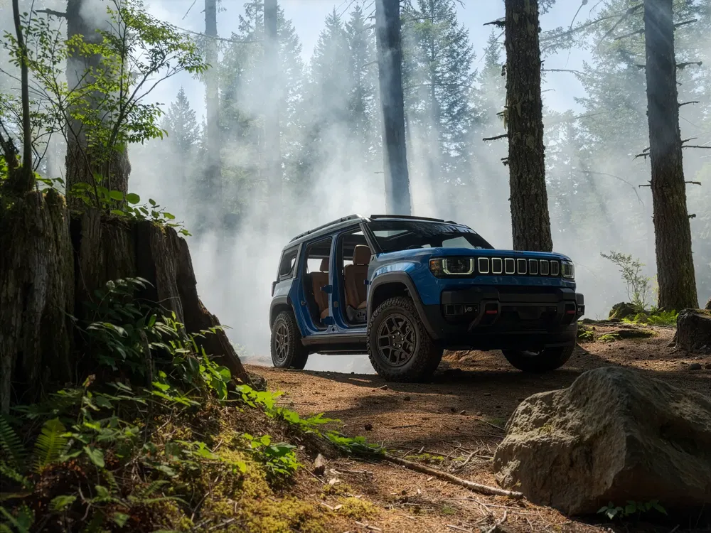 Blauwe GMC Hummer EV in bos, open dak, klaar voor off-road avontuur.