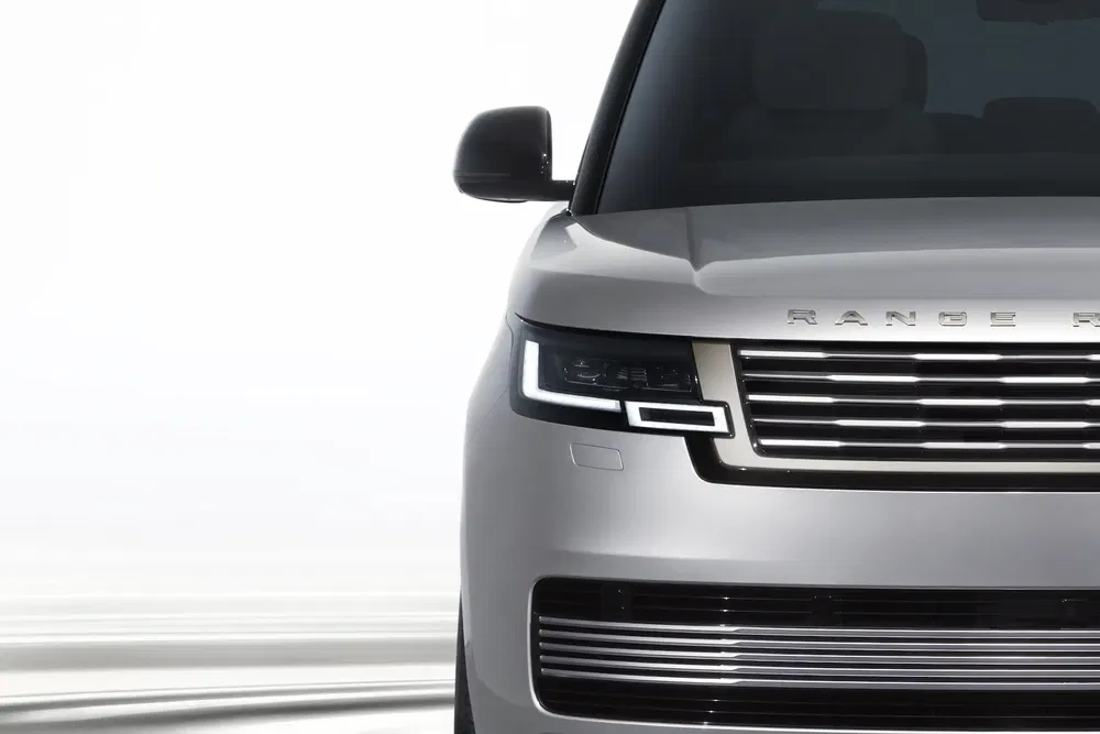 Stijlvolle close-up van een zilveren Range Rover met moderne grille tegen witte achtergrond.