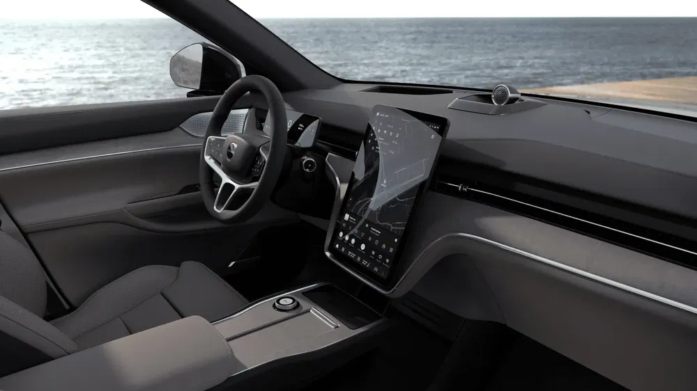 Intérieur de voiture Polestar avec écran tactile géant et volant ergonomique au bord de la mer.