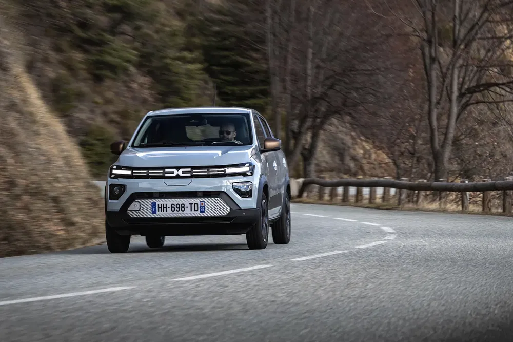 {"fr":"SUV Dacia sur route de campagne sinueuse en hiver, nature boisée en arrière-plan.","nl":"Dacia SUV op kronkelende landweg in winter, bosachtige achtergrond."}