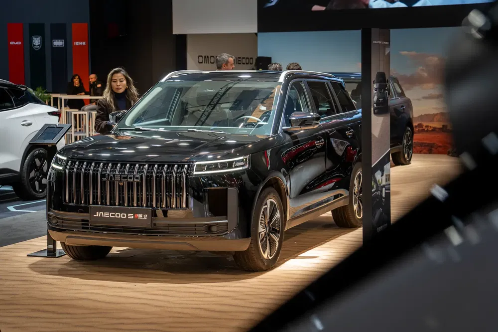 Zwarte Jaecco 5 M2 SUV tentoongesteld op autobeurs met bezoekers.