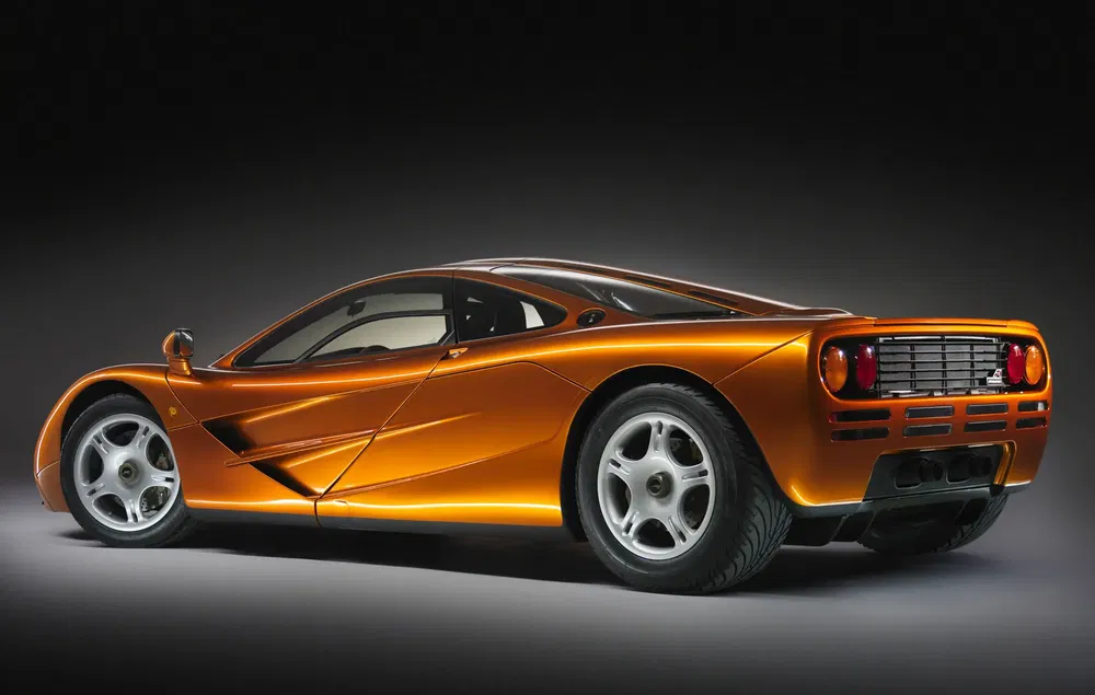 McLaren F1 orange profil arrière, design aérodynamique, éclairage studio.