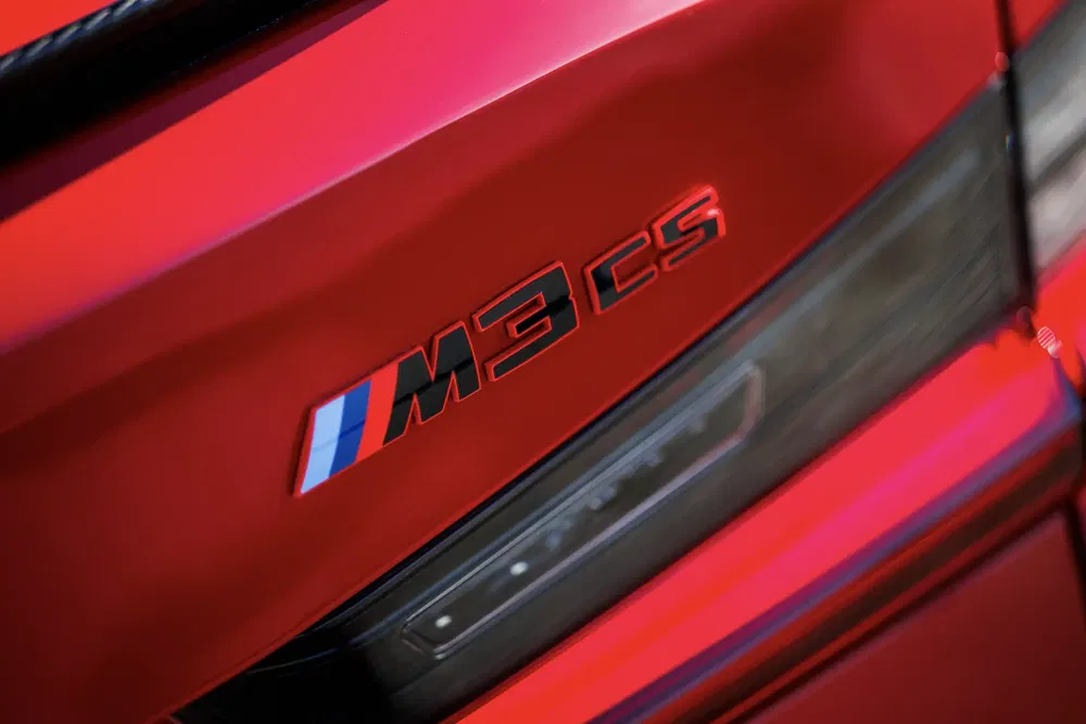 Detail van de BMW M3 CS-badge op een glanzende rode carrosserie.