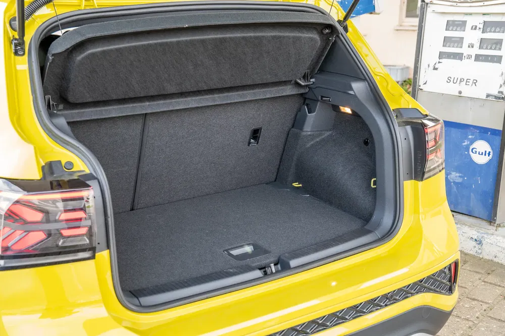 Ruime kofferbak van een gele Volkswagen met opvallende achterlichten, Gulf tankstation.