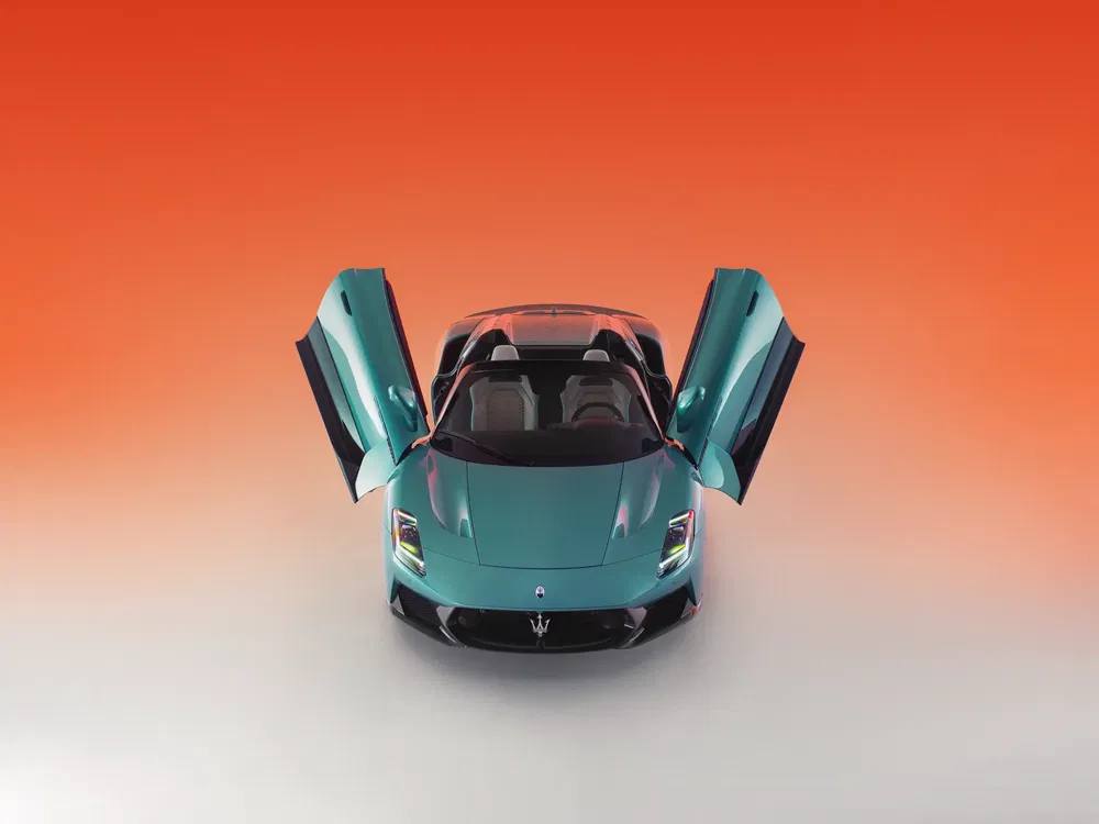 Groene Maserati MC20 sportwagen met geopende vleugeldeuren, oranje verloopachtergrond.