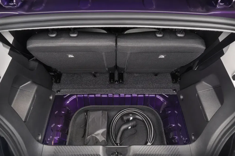 Coffre de voiture électrique avec câbles de recharge rangés, intérieur violet moderne.
