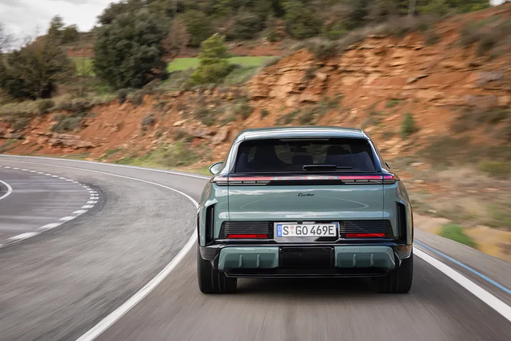 Porsche Taycan Turbo sur route sinueuse bordée de rochers et verdure.